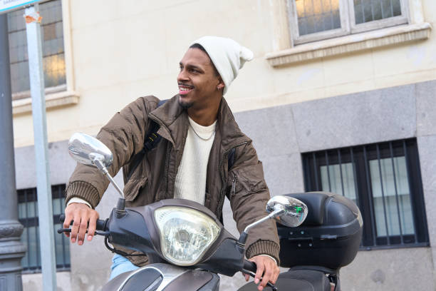 Happy delivery man riding a scooter through the city, dressed in warm winter clothes and enjoying his day while commuting
