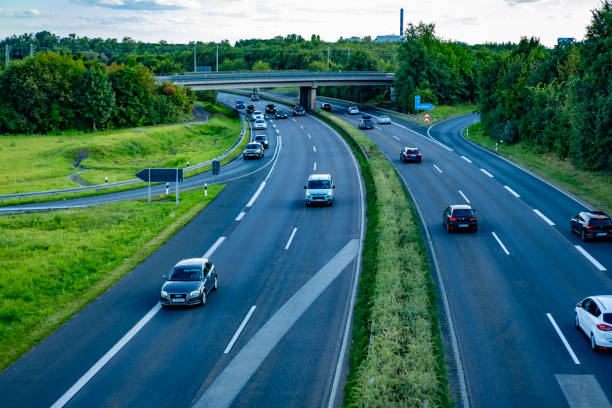 A view of a highway in Denmark with traffic seen in motion blurs, surrounded by scenic autumnal vegetation.
