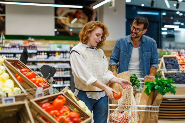 istock Young couple choosing fresh tomatoes in grocery store 2199471106