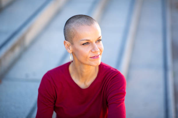 istock Close up older woman with shaved head looking away 2199471994
