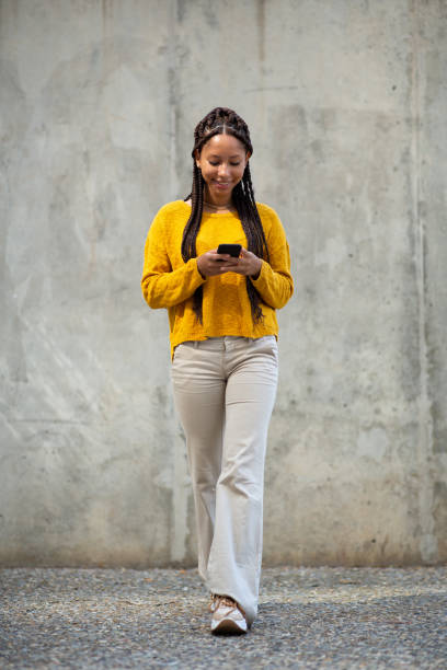 istock Trendy young african woman walking outside using her mobile phone 2199472175
