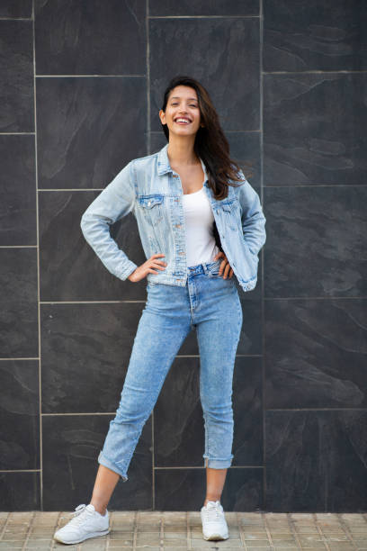istock Full length cool young woman smiling by wall 2199472418