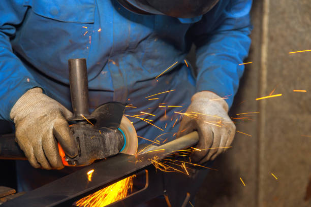 istock Man uses angle grinder to shape metal in workshop creating sparks during evening hours 2199476349