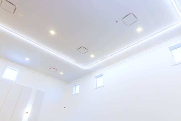 Spacious, well lit room with sleek white ceiling showcasing recessed lighting, small windows.