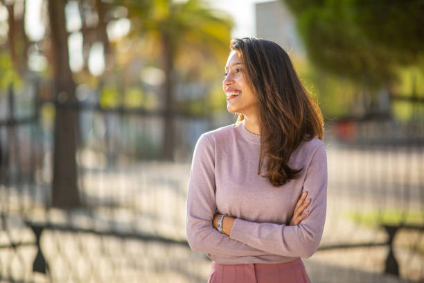 smiling young woman outdoors with arms crossed