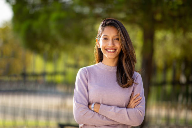 istock smiling woman with arms crossed in park 2199483396