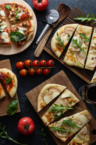 istock Sliced pizzas with sausage, ham and pears, basil and arugula 2199485100