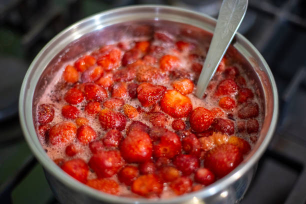 A nickel-plated saucepan with strawberries boiled in sugar syrup. Fruit preservation, jam.