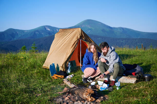 istock Two campers enjoying serene view of rolling mountains under clear sky. 2199486397