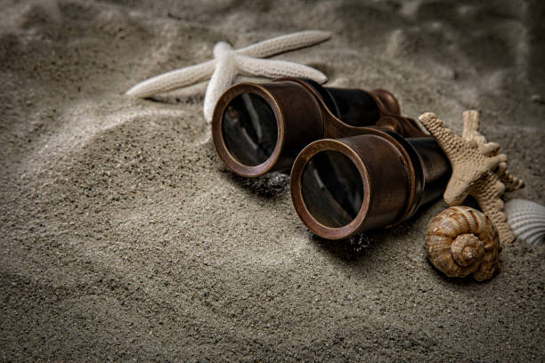 Low angle close up of black binoculars laying on a wood table.