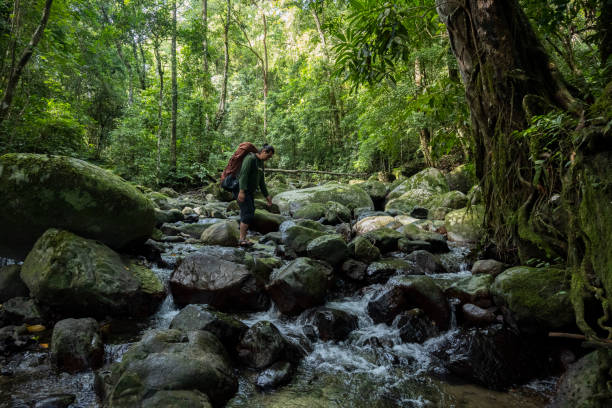 istock Man with backpack walking in the river-Stock Photo 2199505352