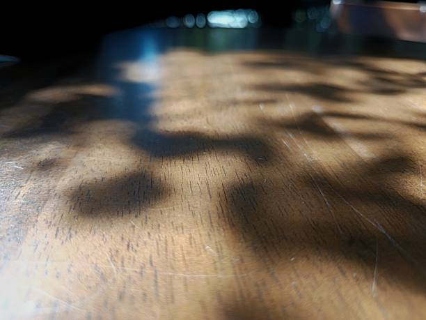 istock Artistic play of light and shadow on a wooden surface, capturing an abstract and tranquil atmosphere. The dappled sunlight creates soft, organic patterns that dance across the textured wood grain, evo 2199523389