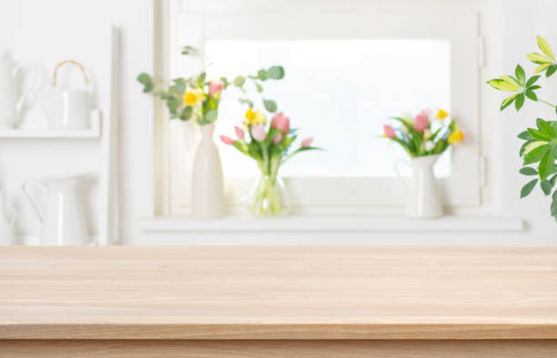 istock Wooden table top with copy space on blurred window background decorated with colorful spring flowers 2199523970