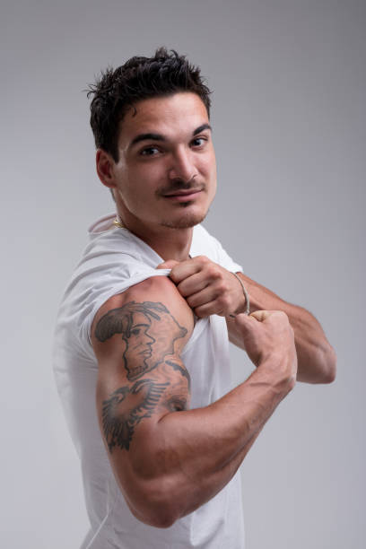 istock Young man showing his tattoo on grey background 2199529041
