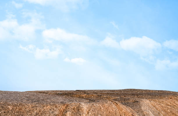 Rock stones with texture surface with blurry blue sky,cloud background,Summer background Rock podium for product presentation.Aerial view Edge Cliff Rock mountain with blurred sky in sunny day summer