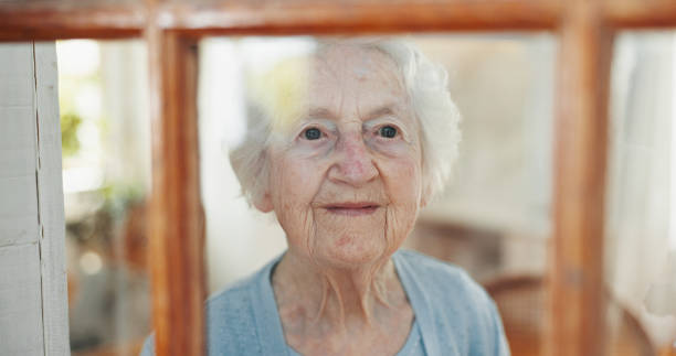 istock Thinking, window and peace with old woman in living room for memory, reflection and mindfulness. Smile, inspiration and vision with senior person in nursing home for retirement, decision and wonder 2199533024