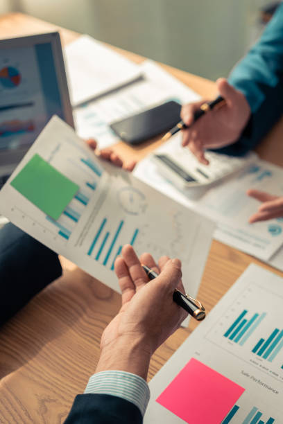 istock Business Colleagues team analyzes financial data at table in modern office about business strategy during discussion. There are financial charts and graphs on the table. Close-up vertical image 2199541178