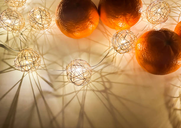 Bright orange fruits illuminated by decorative lights creating an enchanting ambiance on a surface