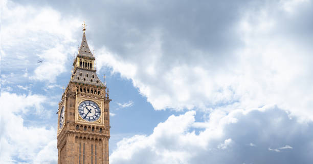istock Big Ben iconic clock tower bathed in daylight, emphasizing the golden accents and intricate design against the backdrop of a cloudy sky, for promoting London historic landmarks. 2199556047