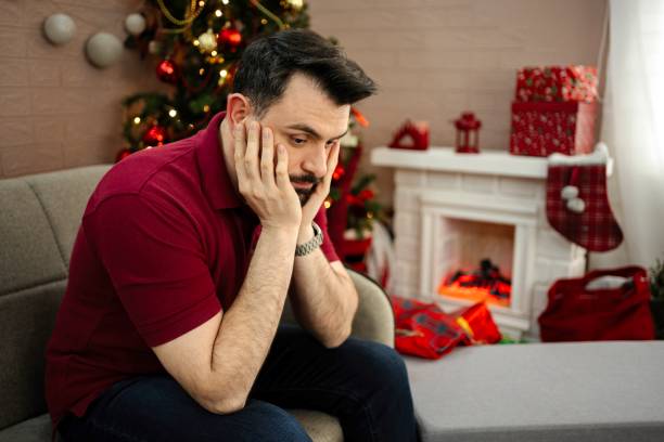 istock Sad man sitting on sofa during Christmas holidays 2199557571