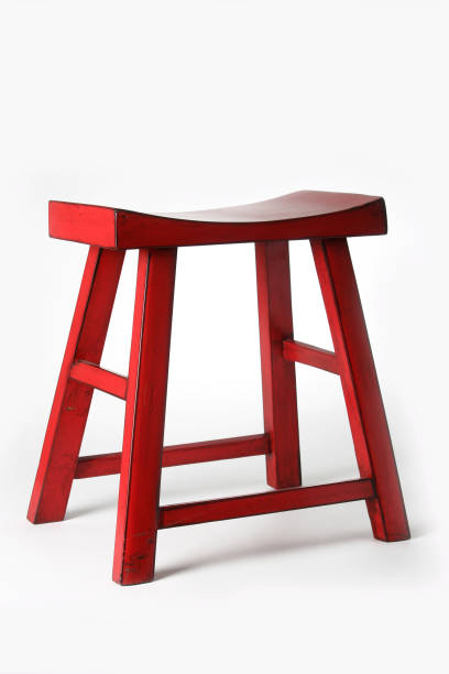 istock Red wooden stool featuring curved saddle-style design, offering minimalist seating comfort 2199558036