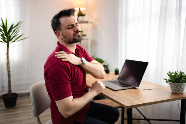 istock Man working from home suffering from shoulder pain massaging his shoulder 2199558091