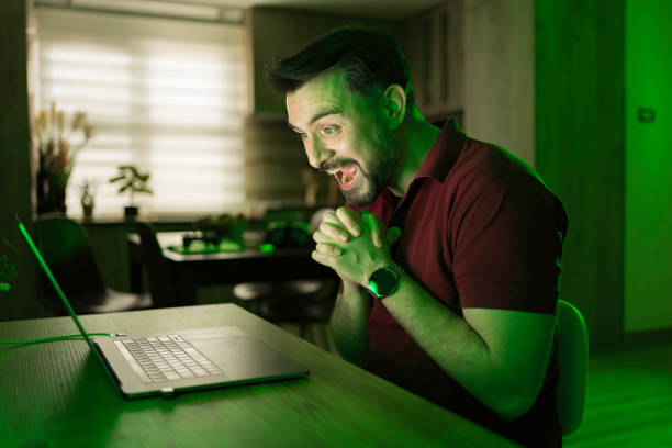 istock Excited man celebrating success while using laptop at home at night 2199560466
