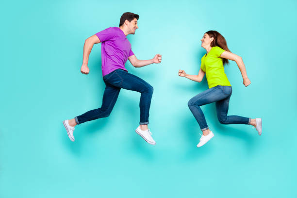 istock Full length body size profile side view of nice attractive sportive active cheerful cheery couple running jumping in air having fun isolated over bright vivid shine vibrant green turquoise background 2199561474
