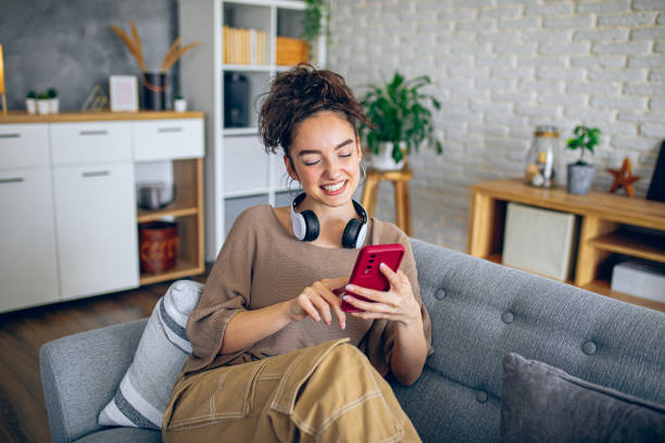 istock Happy woman using phone while relaxing in the couch at home 2199567870