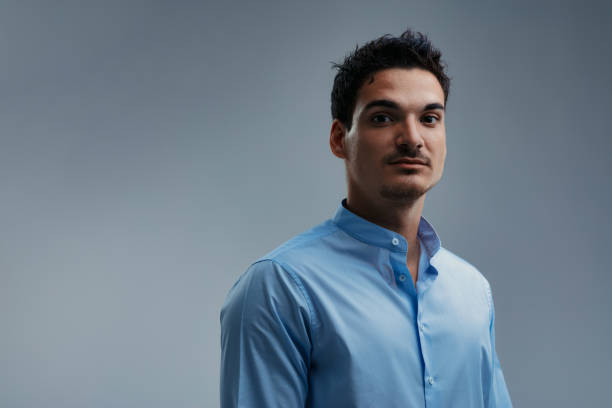 istock Confident young man wearing a blue shirt, looking at the camera 2199567975