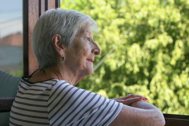 istock elderly  woman looking at her garden from the window 2199569314
