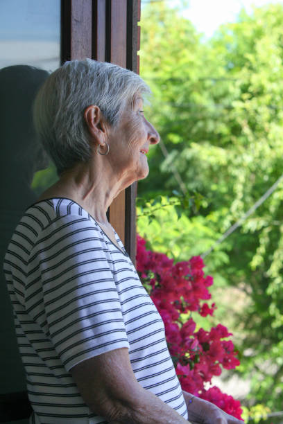 istock elderly  woman looking at her garden from the window 2199569329