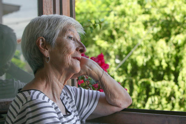 istock elderly  woman looking at her garden from the window 2199569331