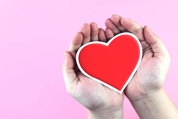 istock Red paper heart in hand on pink background. 2199569948