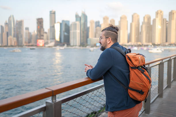istock Man gazing at Dubai marina skyline reflecting on waterfront 2199570082