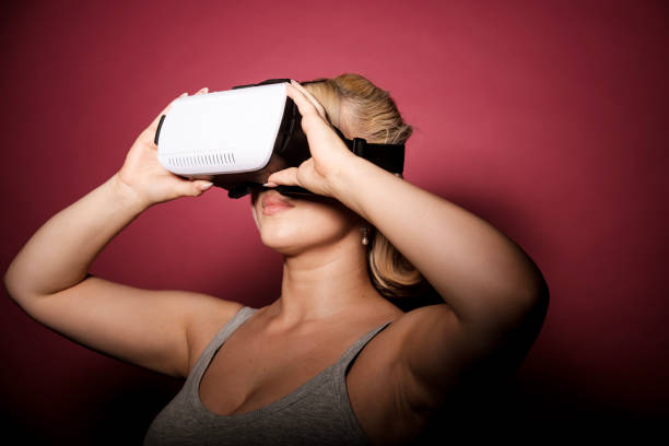 istock Blonde woman wearing virtual reality headset exploring metaverse 2199578329