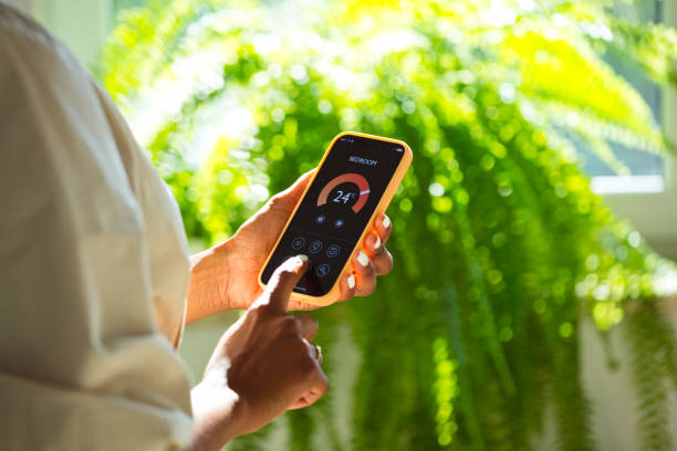 istock Woman using mobile phone to control termostat at home 2199580644