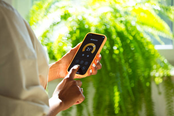 istock Woman using mobile phone to control termostat at home 2199580676