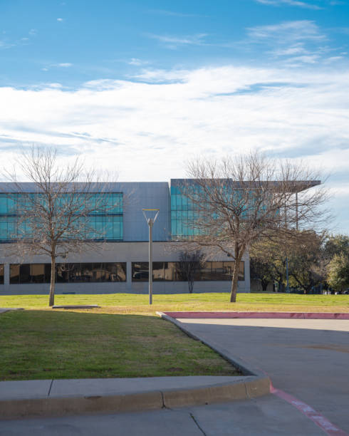 istock Modern campus building complex university college students in Dallas, Texas under sunny blue cloud winter sky, well-trimmed yard landscape, metal fence, sidewalk pathway, education industry 2199582640