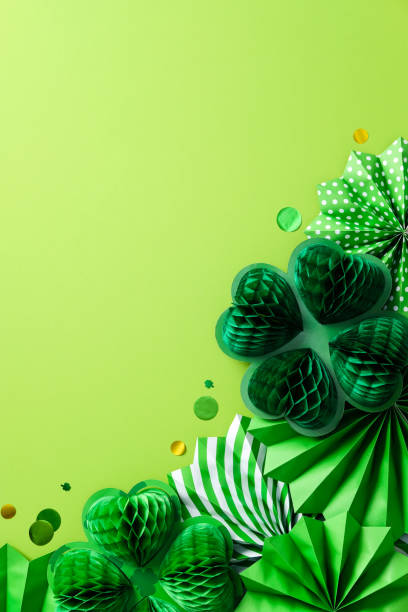 istock Green St. Patrick's Day vertical background featuring paper shamrocks and fans. Flat lay, top view. 2199584224