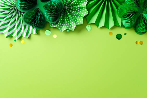 istock Happy St Patrick's Day concept. Green festive background with paper decorations. Top view border of green paper fans, honeycomb shamrocks, and confetti. 2199584474
