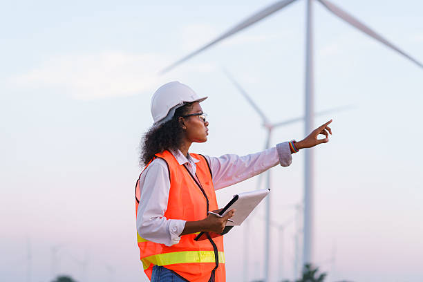 istock A young African-american engineer is recording data from a wind farm survey in a business generating electricity from wind turbines with a sunset background. 2199592483