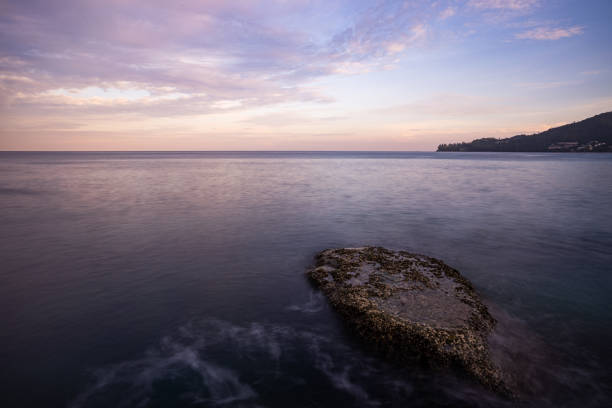 Long exposure image of Dramatic sky seascape with rock in sunset scenery background