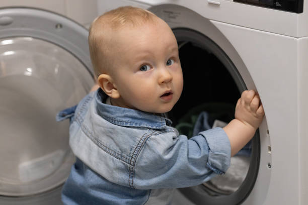 istock Curious little child near wash machine. 2199596230