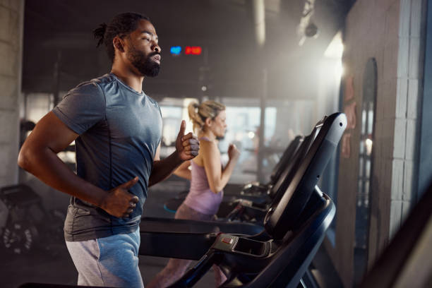 istock Determined black sportsman jogging on treadmill in a gym. 2199599628