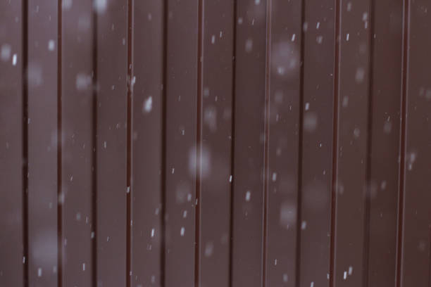 Perspective along a metal fence. Snowflakes falling down. Background. Texture.