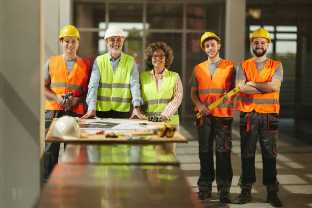 istock Team of happy architects and manual workers at construction site. 2199602649