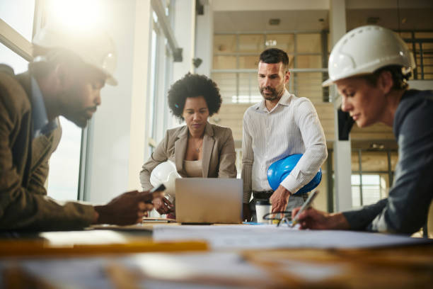 istock Team of architects working on plans at construction site. 2199603060