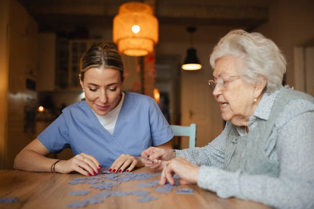 istock Friendly caregiver and elderly patient working on puzzle together, having fun. 2199605551