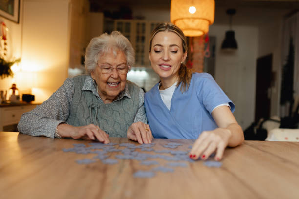 istock Friendly caregiver and elderly patient working on puzzle together, having fun. 2199605647